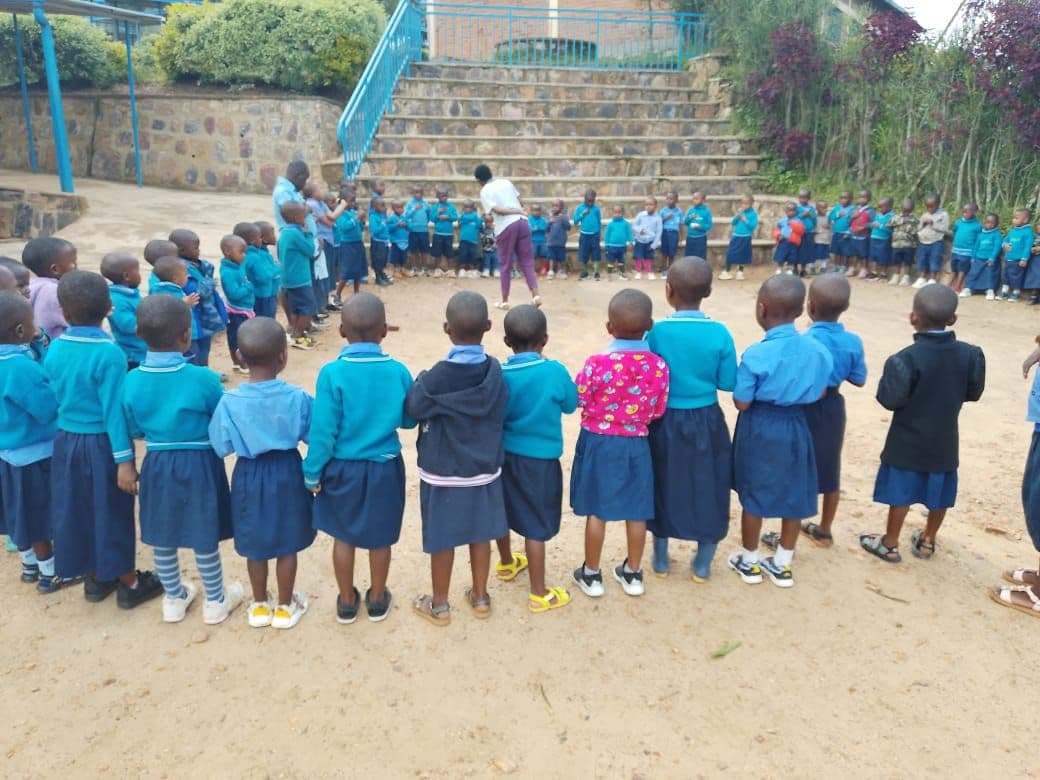Enfants de maternelle en uniforme bleu formant une ronde dans la cour de Janja